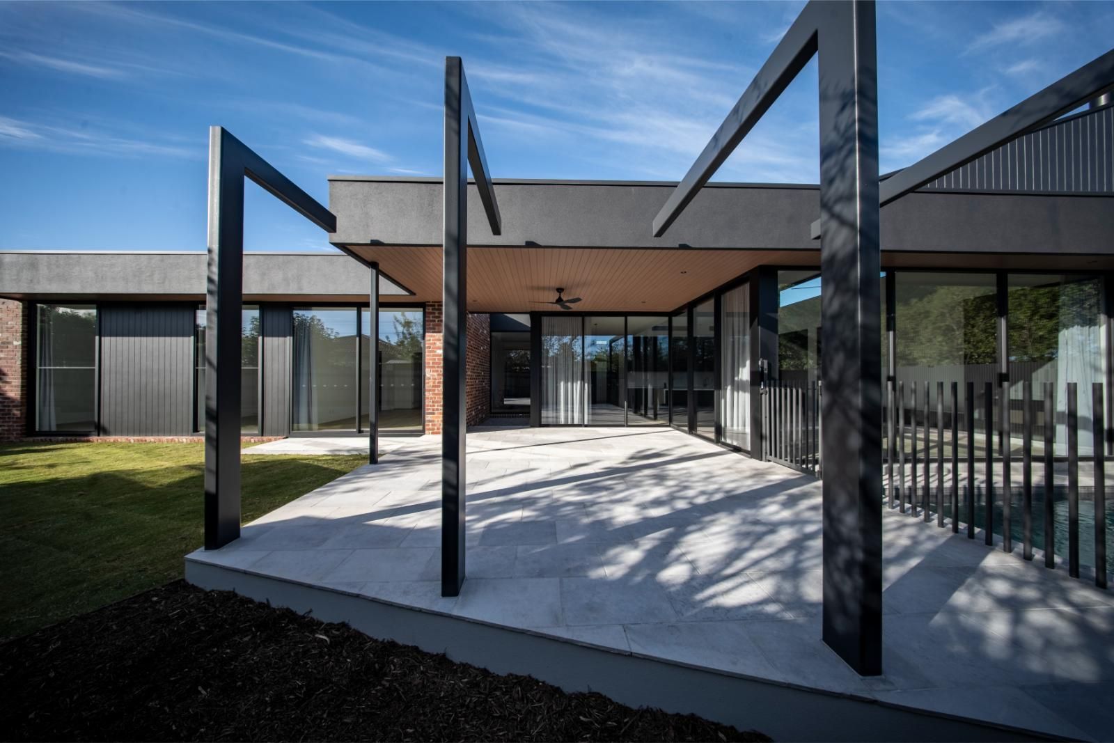 Rear of the Wheelers Hill knockdown rebuild, with full-height glazing opening to a covered alfresco and lawn