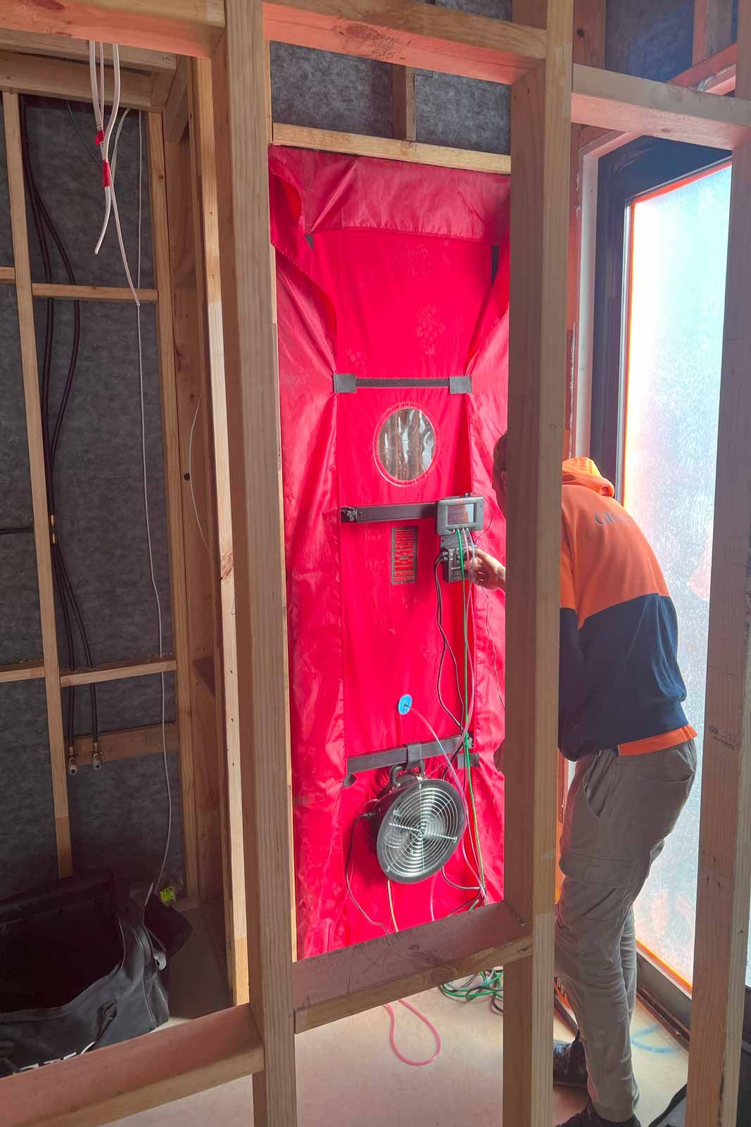 Blower-door test fan fitted into a doorway during construction, used to check airtightness