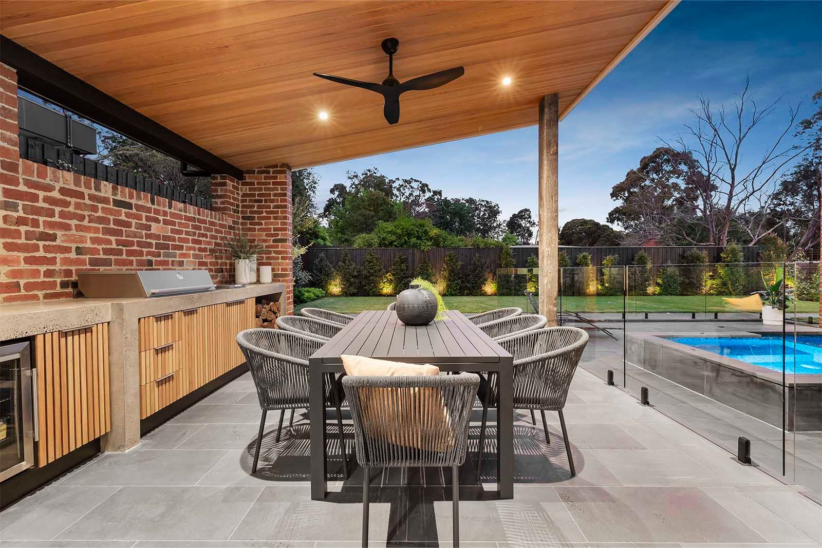Outdoor kitchen and dining under a timber-lined alfresco roof