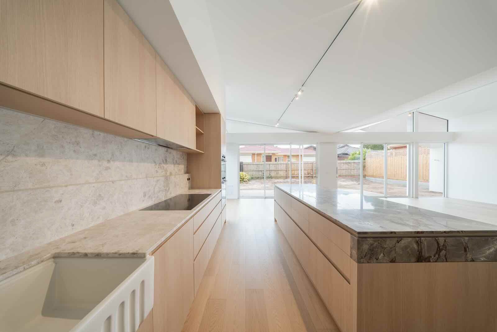 Renovated kitchen with a long stone-topped island and timber floors