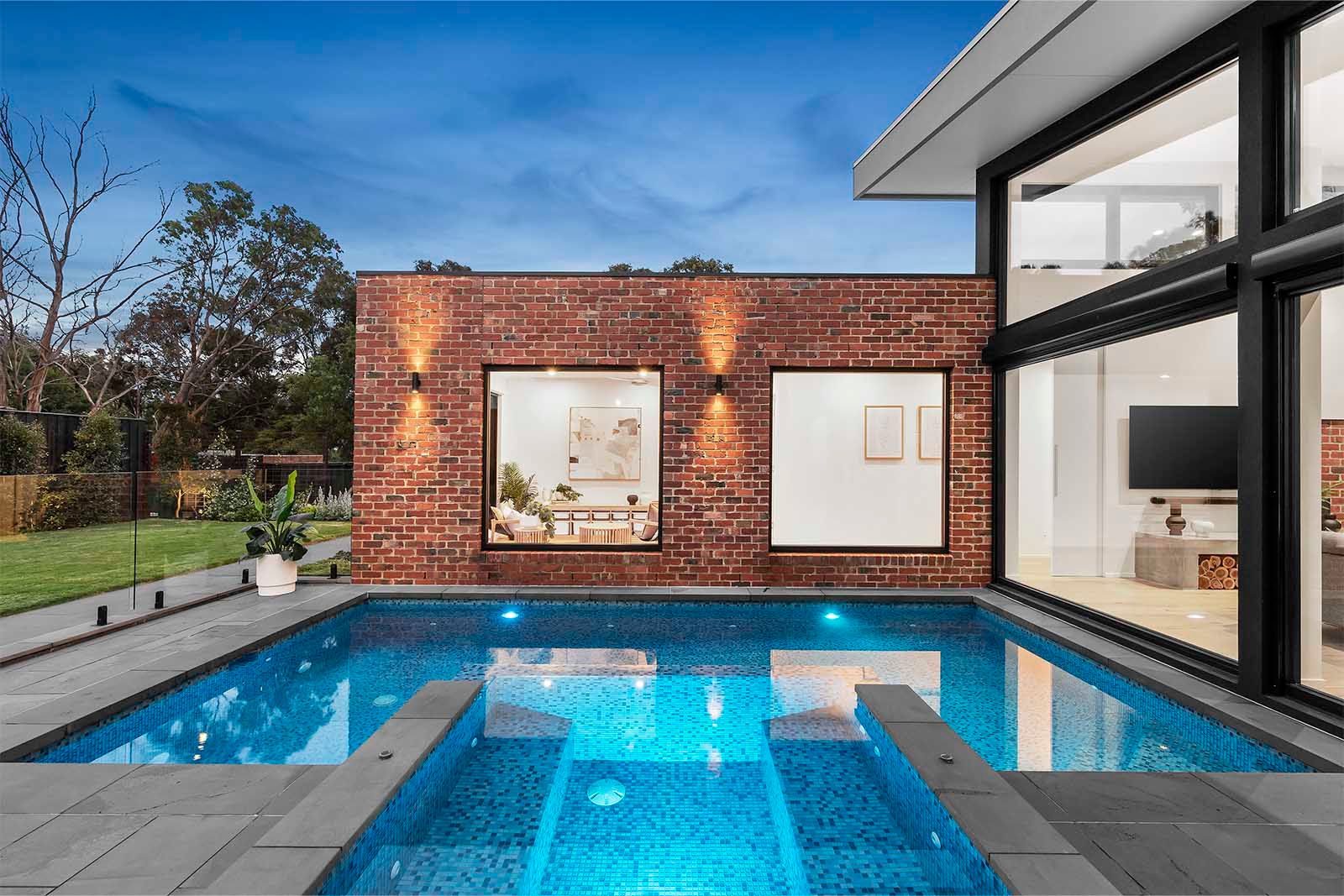 Pool and spa beside the brick wing of the Warranwood custom home