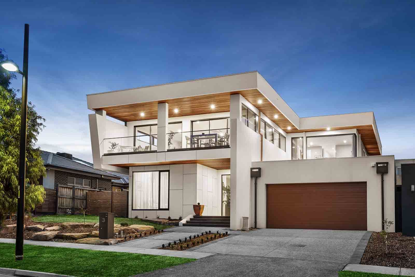 Bundoora home at dusk: a two-storey white facade with a timber-lined balcony overhang
