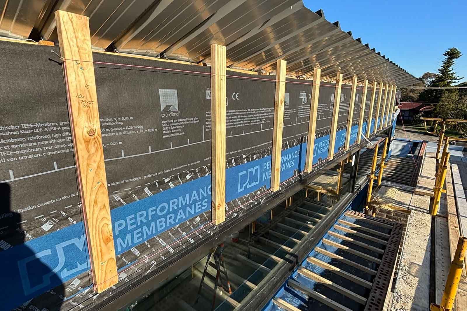 Wall framing wrapped in a performance membrane on an upper level