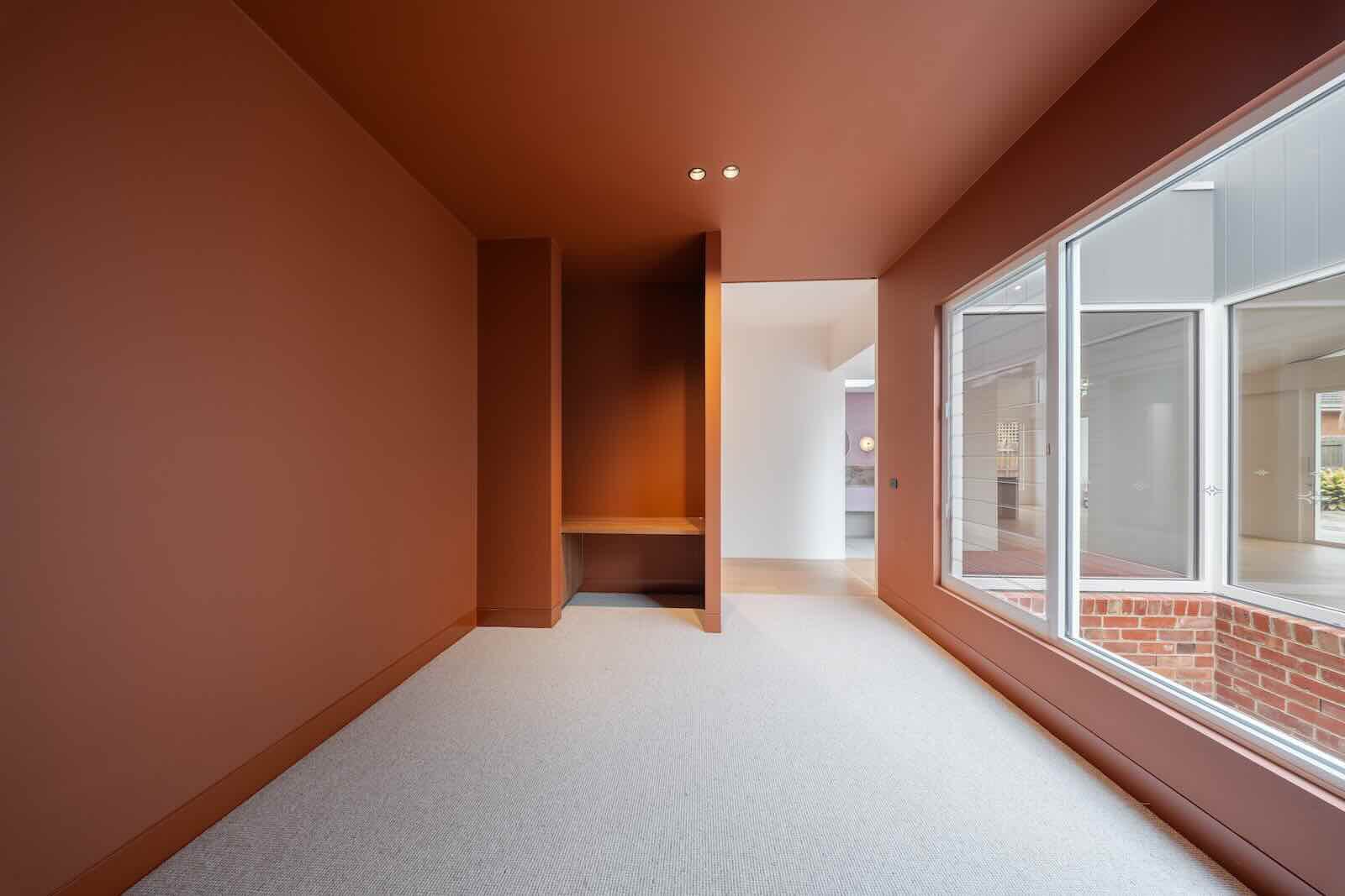 Room finished in deep terracotta with built-in joinery