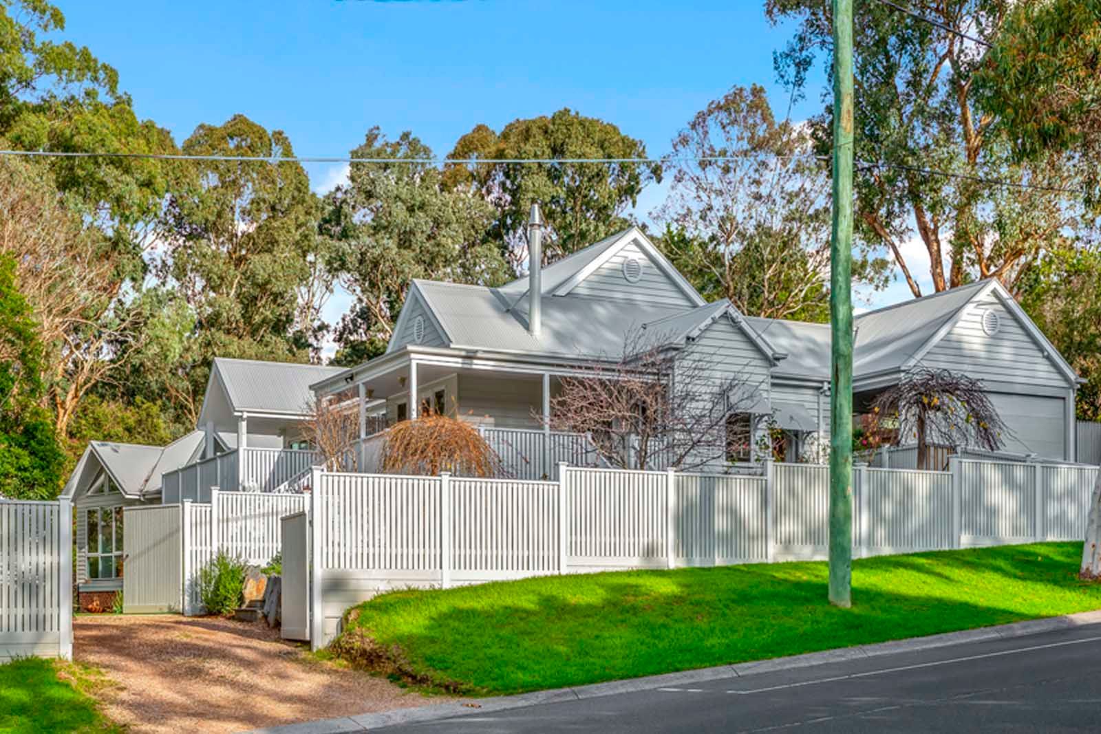 Street view of the extended weatherboard home and white picket fence