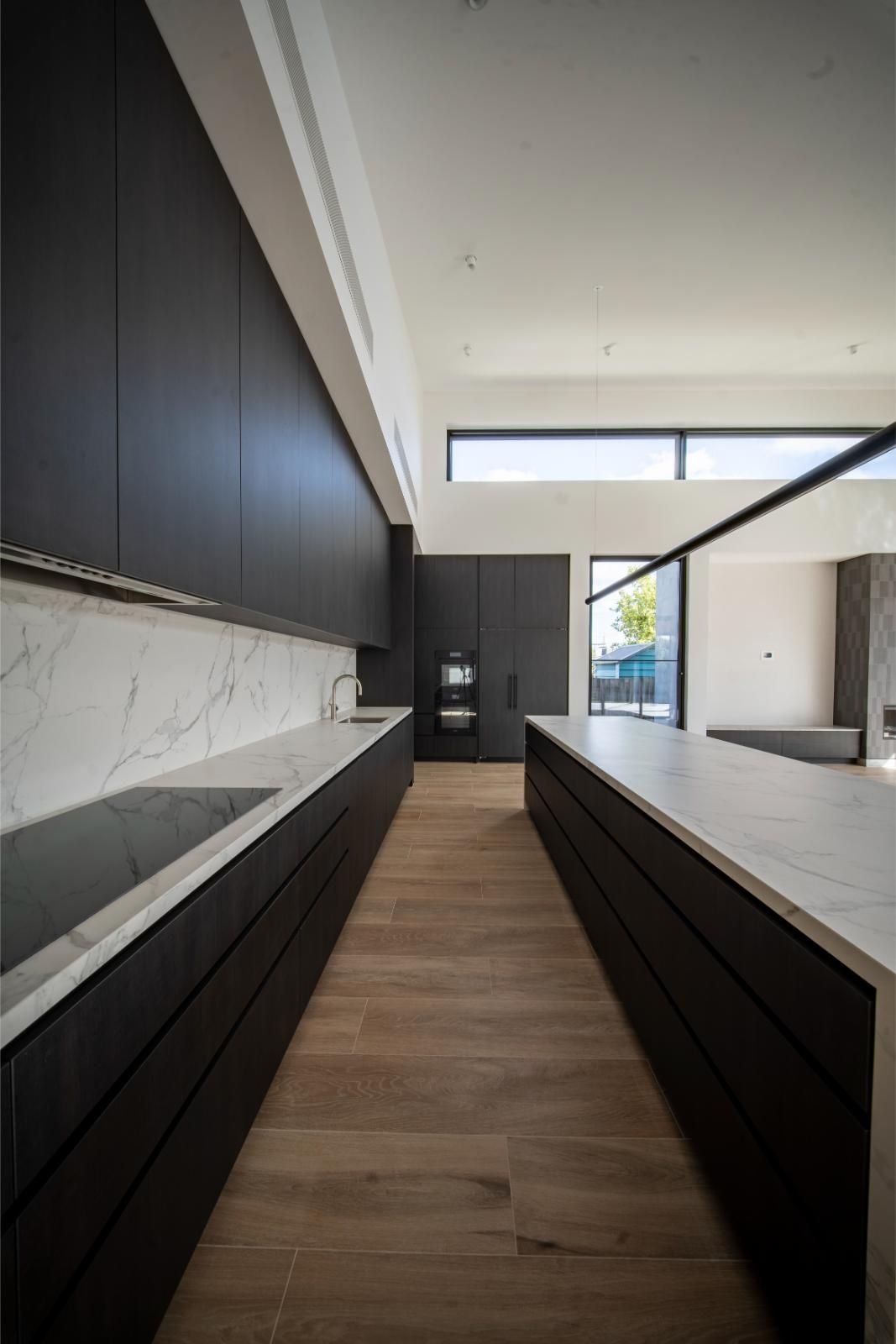Kitchen with dark timber joinery, marble-look benchtop and long island
