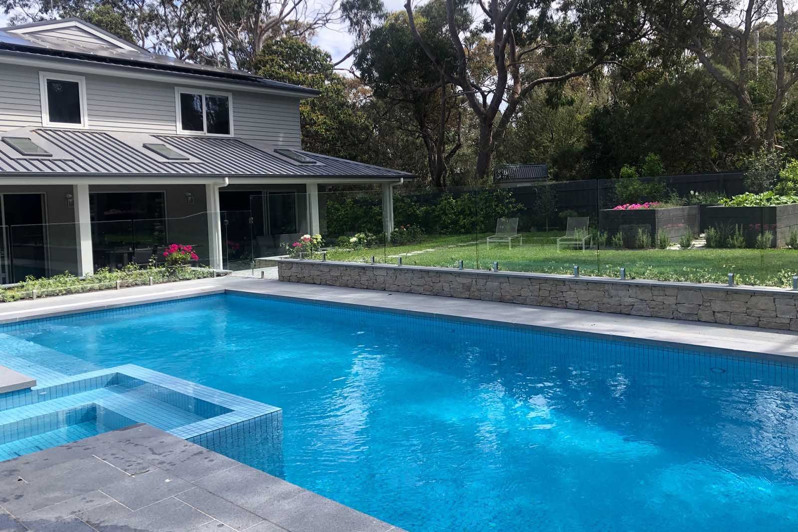 Heated pool and spa with a lawn and covered terrace behind