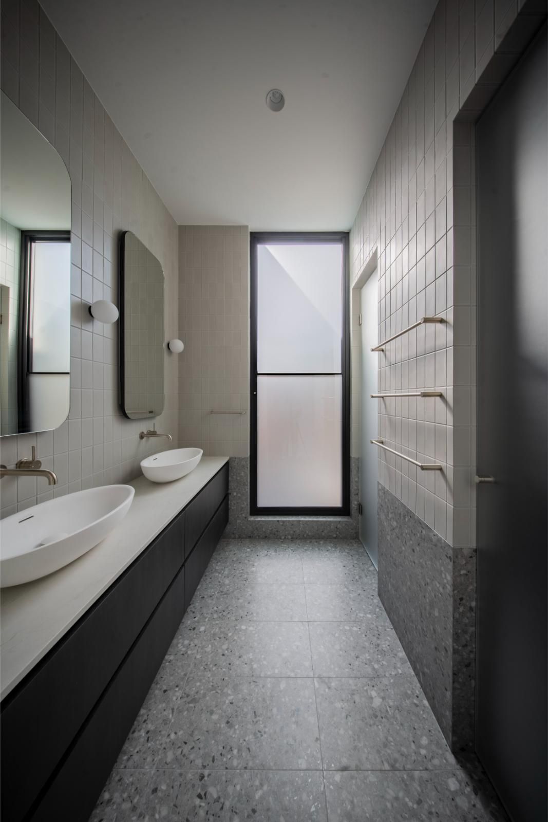 Ensuite with a stone basin, round mirror and tall window