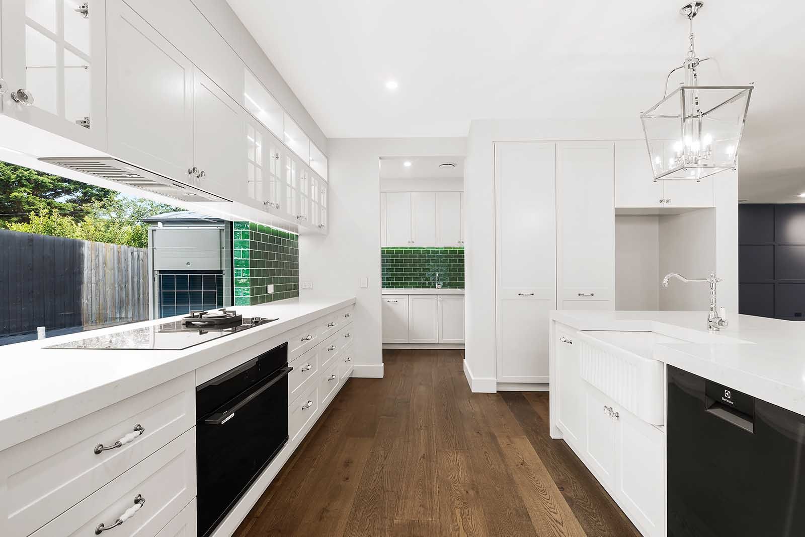 White kitchen with a long island and timber floors