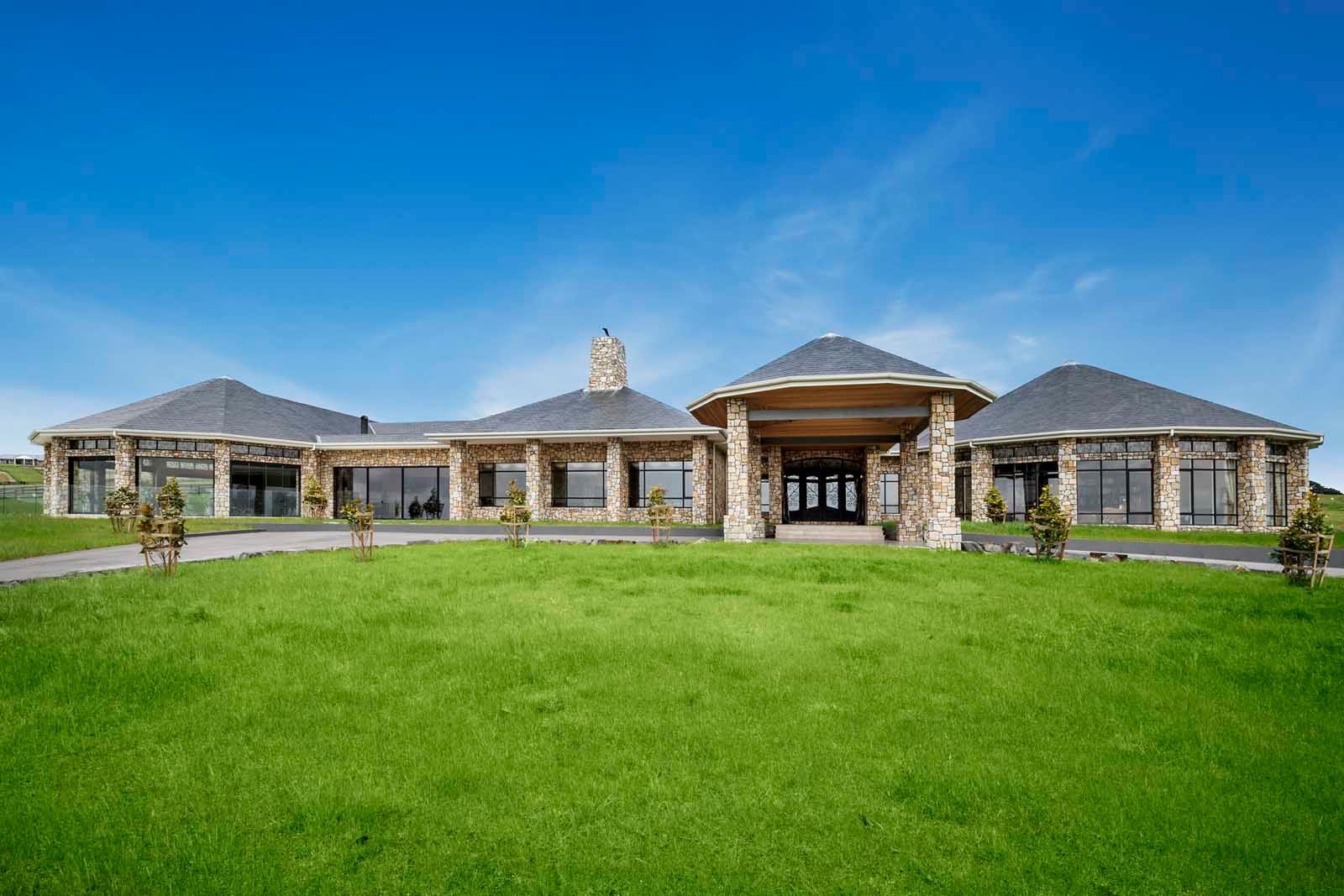 The home across a broad lawn under a blue sky