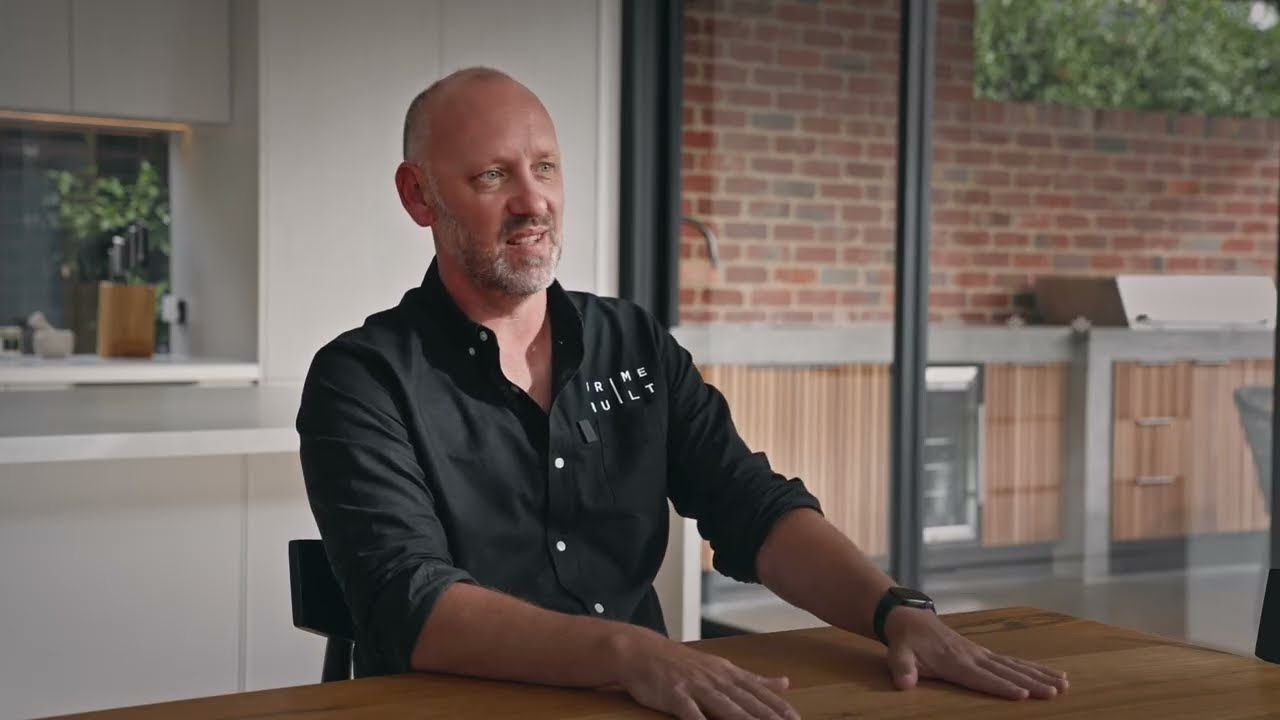 Chris Cahill, Director of Primebuilt, seated at a timber table in a finished kitchen